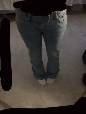 Ljusblå jeans från lager 157 - Ljusblå jeans med broderad detalj på bakfickan och dubbla knappar i midjan. Klassisk femficksmodell med raka ben och normal passform. Jeansen har en snygg tvätt och är perfekta för dig som gillar en enkel men unik look. Använda en gång. Dom är en kort modell jag är 159cm och dom sitter perfekt på mig i längden. Även lågmidjade. 