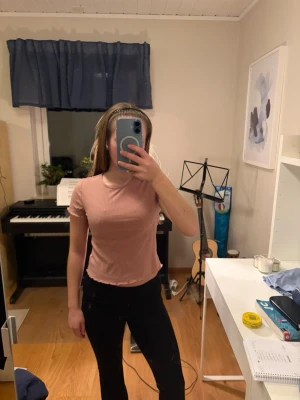 Rosa ribbad topp  - Säljer en ljusrosa ribbad topp från Ellen New York. T-shirten har korta ärmar, är lite croppad  och vågig kant nertill. Supermjuk och stretchig i materialet.