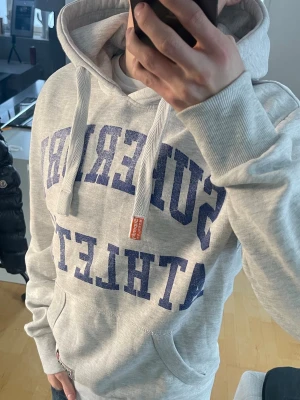 Vintage 2000s Superdry hoodie (Limited edition) - Säljer nu denna sjukt snygga och sällsynta vintage 2000s Superdry hoodie ur en limiterad upplaga😊 Säljs ej längre i butik och är därav mycket eftertraktad! Hoodien passar perfekt till allt och är både varm och bekväm🤩 Mycket bra skick. Finns en väldigt liten fläck som med 99% säkerhet går bort i tvätten, se sista bilden. Skriv vid funderingar 📲