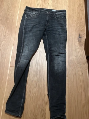 Replay svarta slim jeans - Säljer ett par svarta Replay jeans med snygga slitningar och klassiska fem fickor. Jeansen har en smal passform och är tillverkade i ett mjukt jeansmaterial med stretch. Snygga detaljer på bakfickorna och diskret Replay-märke i midjan.