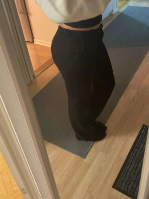 Svarta kostymbyxor - Säljer ett par svarta byxor med hög midja och wide fit. Byxorna har en stilren look med raka ben och diskreta fickor på sidorna. Perfekta för dig som gillar en avslappnad men snygg stil. Passar till många olika outfits.