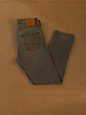 Jack & Jones relaxed jeans blå 31/32 - Säljer ett par blå jeans från Jack & Jones i modellen Relaxed/Chris. De har en avslappnad passform, klassisk femficksdesign och raka ben. Jeansen är i ett ljusblått tvättat denimtyg med knappgylf och bälteshällor.