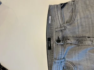 Replay ljusgrå jeans - Säljer ett par ljusgrå jeans från Replay med klassisk femficksmodell och raka ben. Jeansen har svarta detaljer på fickorna och en snygg patch bak i midjan. Materialet är mjukt jeans-tyg som sitter skönt och passar till det mesta.