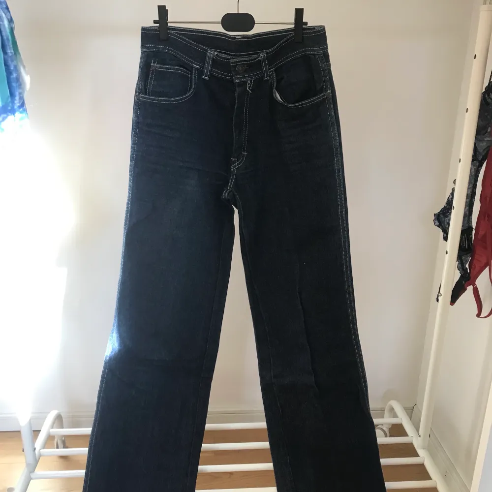 Otroligt coola mörkblå jeans från vintage-affären Pop Stockholm. De har vita kontrastsömmar och är långa i benen. Jag på bilden är ca 172 cm. Jeansen är rätt lågmidjade och vida, svagt utsvängda. Bra skick men använda. . Jeans & Byxor.