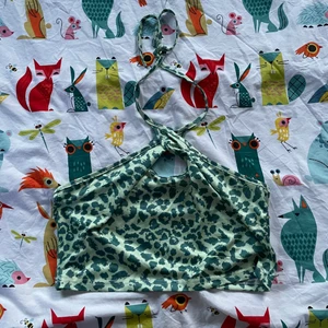 turtleneck topp - Säljer en grön leopardmönstrad halterneck topp som man knyter runt halsen vilket skapar en fin cirkel runt brösten, det är en magtröja
