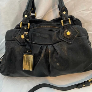 Marc Jacobs väska - Marc Jacobs classic q, säljer nu min marc jacobs väska i en så klassisk modell! Den är i fint men använt skick, dust bag följer med! Man kan bära den i handen, på armen eller över axeln! Bra med utrymme! Längre Axel rem medföljer 