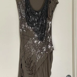 Next klänning XS - Använd en gång. Många mönster som silver spindelnät och svarta pärlor. Många hål. Brungrön. Köparen står för frakt.