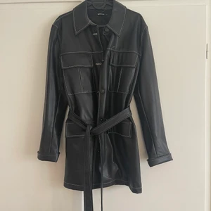 Svart kappa i läderimitation - Svart kappa/jacka i läderimitation från Gina tricot, storlek M, fint skick endast använd några få gånger.