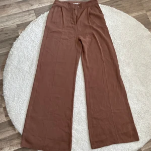 Vida byxor  - Ett par luftiga och vida bruna byxor från NA-KD. En oerhört fin färg som är väldigt trendig nu. Använda en gång men de var för små för mig, därför får någon annan lycklig tjej bära upp dessa. De är ganska långa så bär gärna med ett par klackar om du är under 1.65cm lång. Pris 160kr. Kan mötas upp  i Halmstad och Kalmar annars står köparen för frakt. 