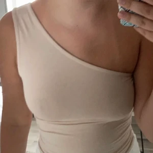 Body från NA-KD  - Body från nakd i bra skick, stolek XS men passar upp till M. Det är en string body och i färgen beige, på bilden så ser ni även att den är one shoulder, tänkte sälja för 70kr inklusive frakt ❤️