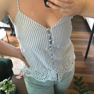 Randigt Linne - Sött vit- och blårandigt linne i fint skick. Lite skrynkligt på bild. Säljer då det är för litet för mig. Kan mötas i Uppsala eller skicka (frakt 45kr + 10kr kostnadstillägg om SafePay önskas). Se min profil för fler fina plagg.