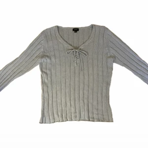 Ljusblå stickad tröja - Ljusblå stickad y2k tröja med knytdetaljer, perfekt för vintern! Ser mer gulaktig ut på bilderna men är inte det i verkligheten. Från H&M i storlek M. Har ett litet hål i ryggen, priset kan därför diskuteras