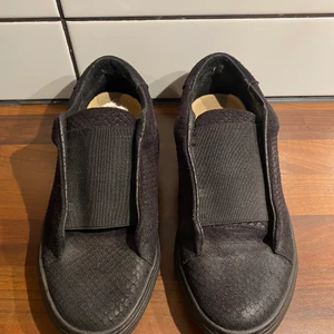 Vårskor från Åhléns, Wera. - Obetydligt använda. ”Slitningarna” beror på dåliga ljuset när bilden togs. Svarta i svagt ”reptilmönster”. Otroligt bekväma! Skickas med spårbar frakt 61:- som ingår i priset. Endast seriösa hör av sig, tack. Nypris 699:-