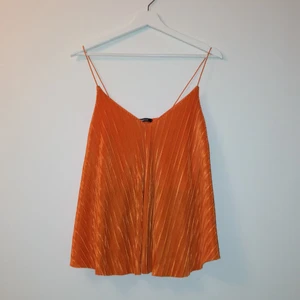 Orange topp  - En orange plisserad topp som faller fint på kroppen. Toppen är ifrån Gina Tricot. Storleken är L men passar även XS-M Köpt för ca 200kr💕 Köparen står för leveransen och betalning sker via swish!