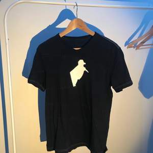 Mörkblå t-shirt med tryck i storlek small. Mönster i tröjan syns på andra bilden, trycket sitter på framsidan.