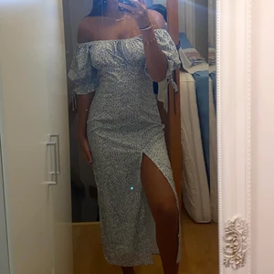 blå klänning med slits - en super fin blå blommig klänning med slits som tyvärr inte kommer till användning. Har aldrig använt innan så den är som ny. Man kan både ha den som offshoulder och med ärmarna upp. Säljer för 150kr + frakt som är 66kr💙💙