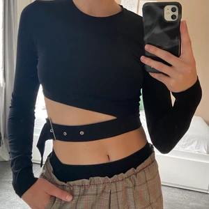 Croptop med bälte  - En svart croptop som är öppen med bälte på sidan. Perfekt om man vill lägga till en ”fun touch” till sin outfit. 