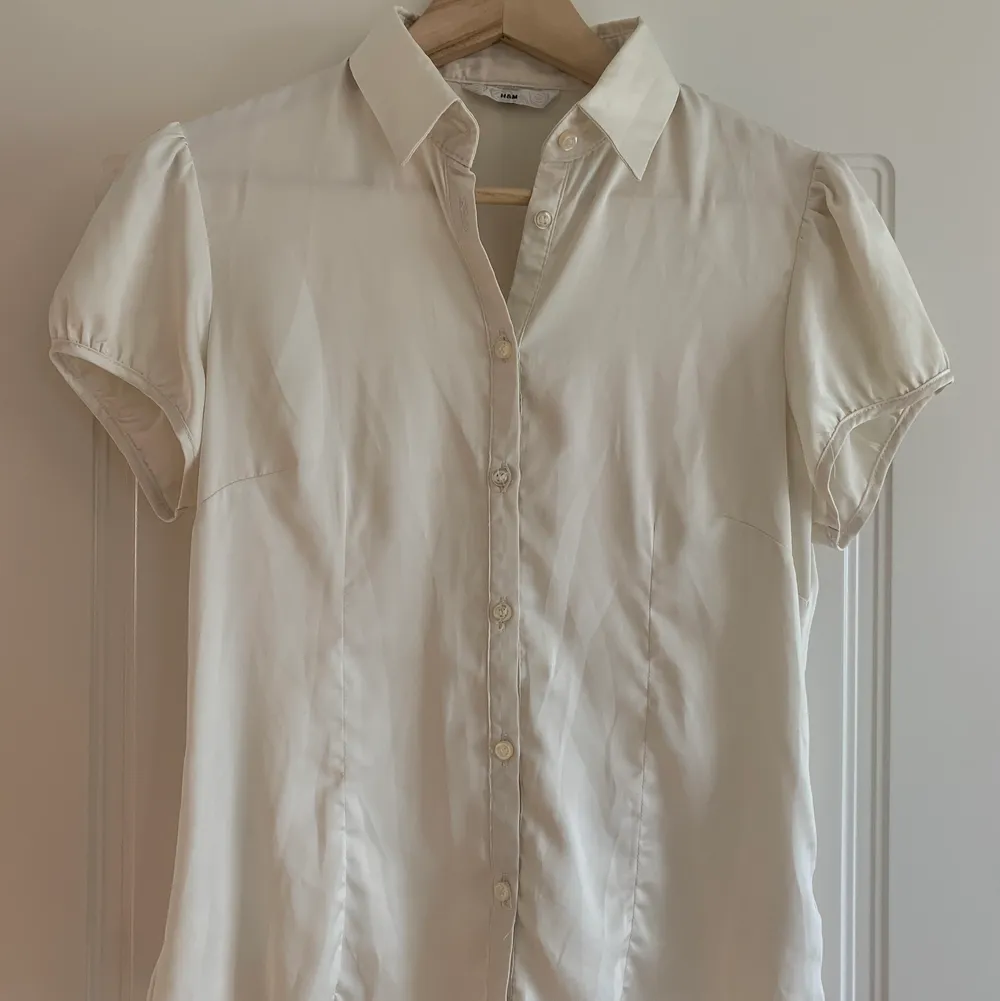 Kortärmad vit skjorta/blus från H&M i silkigt tyg (polyester).. Blusar.