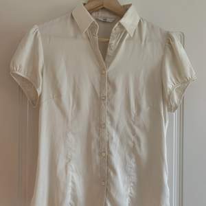 Kortärmad vit skjorta/blus från H&M i silkigt tyg (polyester).