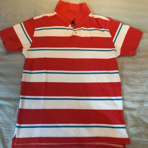 Tommy Hilfiger polo tröja  - Randig polo tröja i färgerna, ljusblå, vit och röd/orange. Tröjan är i mycket fint skick. Den passar 16-18 år (L).