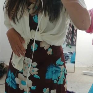 Brun klänning med blommor - Jättefin klänning perfekt till sommaren. Den har snören på sidorna som man kan knyta i ryggen så att klänningen får en fin passform utanpå kroppen. Jättefin färg med mysigt mönster. Den går nästan till knäna på mig (jag skulle gärna ha den lite kortare) då jag endast är 156 cm. Tro den skulle sitta toppen på nån lite längre. 
