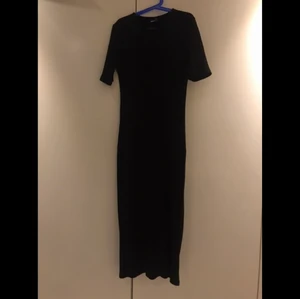 En lång ribbad svart klänning! Stl:M - En jätte fin ribbad svart klänning från Gina Tricot, och är lite öppet vid ena benet!  Stl: M  Köpt för 1 år sedan och är som ny, och ger en fin form!!