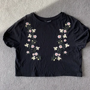 Söt kort topp med brodyr stl M - Svart kort topp med broderade blommor. Sparsamt använd. Djur- och rökfritt hem