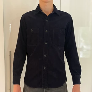Uniqlo Overshirt Strl:S - Detta är en manchester overshirt i väldigt bra skick, med två stora fickor. Den är aldrig använd och har en väldigt fin mörkblå färg. Ett perfekt plagg för dig, den matchar med allt! 