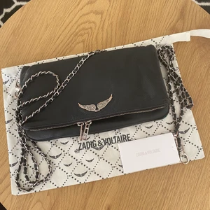 Zadig Voltaire väska - Jättefin väska ifrån Zadig Voltaire. Har haft den ett bra tag så det finns tecken på användning. Det har blivit lite korrition vid märket, kedjan och även dragkedjan. Men det är inget man ser jätte tydligt på långt håll. Man får med långa och korta bandet och dustbagen. Kan skicka fler bilder om det önskas. Kan tänka mig gå ner lite i pris vid snabb affär💞
