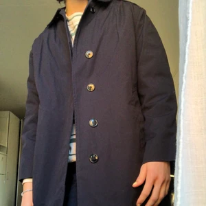 Mörkblå trenchcoat - Säljer en avtagbar vadderad trenchcoat i färgen mörkblå. Storlek är oklar, men skulle säga ish Medium/Small. (Man får inte plats med så tjock tröja under). Lite frakt tillkommer 💙 Pssss den är mycket snyggare irl än på dessa bilder haha