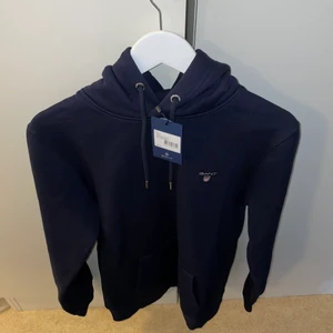 Gant Hoodie Herr (helt oanvänd!) - Navy Blue Gant hoodie storlek M i regular fit. Köpt i Johnells för 1000 kr, helt oanvänd BARA testad. Taggen och kvitton finns kvar. Skriv för fler bilder och info! Köparen står för frakt