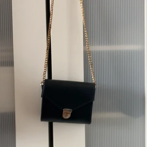 Svart Väska. - En svart väska avänt ett tag men tröttnat. Öppningen är lite rostig. 