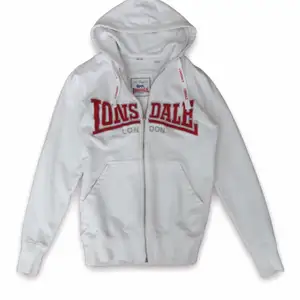 Supernsnygg vit vintage Lonsdale zip up hoodie i storlek XS. Den är i bra skick.  Så snyggt med låga jeans😍
