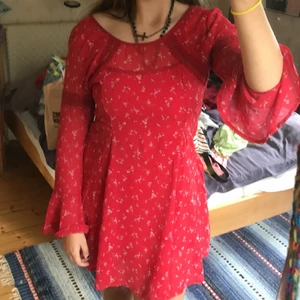 Röd klänning - Söt sommarklänning med små rosa blommor. Den är kort i modellen och har meshtyg över en röd underklänning. Ärmarna är vida och jättefina. Det är även röda broderade ”band” typ vid bröstet och på ärmarna. Den är ganska bred urringning men det är skitsnyggt. Det finns en dragkedja i sidan som fungerar perfekt. Endast använd vid ett tillfälle och sen dess har den blivit hängandes i garderoben. Möts gärna upp i Stockholm men kan även frakta. Köparen står för frakt!💕