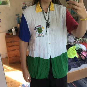 Cool skjorta - Superball skjorta i färgerna grön röd vit gul. Ett jättefint märke på bröstet. Hela skjortan går i de fyra färgerna jag nämnde, även knapparna, som är en väldigt fin detalj. Det syns inte på bilden, men det är en slits på varje sida vid det gröna. Den är extremt ostruken hahaha, men det fixar jag om du vill köpa!🥰Möts gärna upp i Stockholm men kan även frakta. Köparen står för frakt!💕