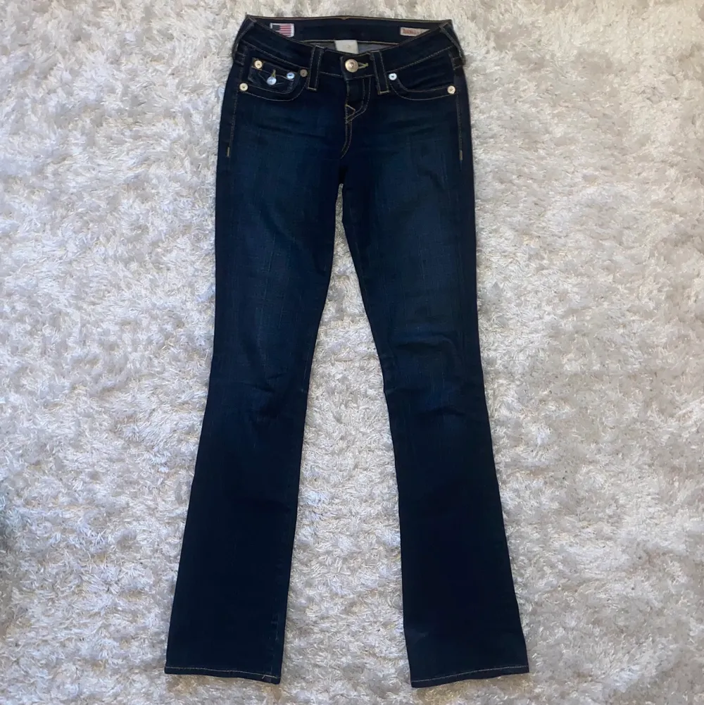 Coola lågmidjade bootcut jeans från True Religion med en mörkare ton, storlek 23 som passar perfekt på mig och jag är 174 cm. Innerbenslängden är ca 83 cm och midjemåttet ca 73 cm! Inte säker att jag vill sälja så kom med bra bud💕Köparen står för eventuell frakt. Jeans & Byxor.