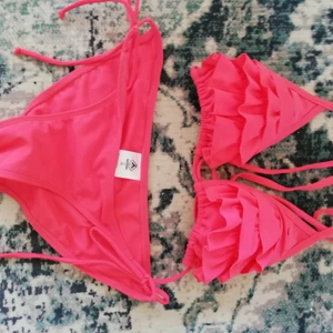 Korall röd bikini från Warp strl. 36 - Jätte söt korall röd bikini från surf märket Warp med volanger, helt oanvänd. 
