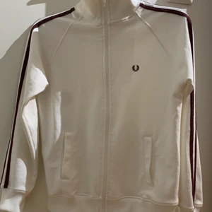 FRED PERRY trackjacket - vit fred perry jacka med vinröda/bruna ränder. begagnad men nästan oanvänd o mycket bra skick. Storlek 38