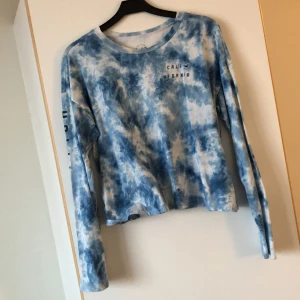 Hollister tröja i blå tiedye storlek M - Skön långärmad bomullströja i storlek M från Hollister. Lös passform med mörkblå text på höger arm och på bröstet. 