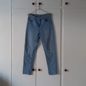 Blå jeans, Never Denim, strl M - Ett par blå jeans, Never Denim, i storlek M. Det är en design med hål på vänster knä. Byxan smalnar av vid ankeln. Använda men i fint skicka, fick dem men aldrig själv använt dem så säljer. Pris: 80 + frakt
