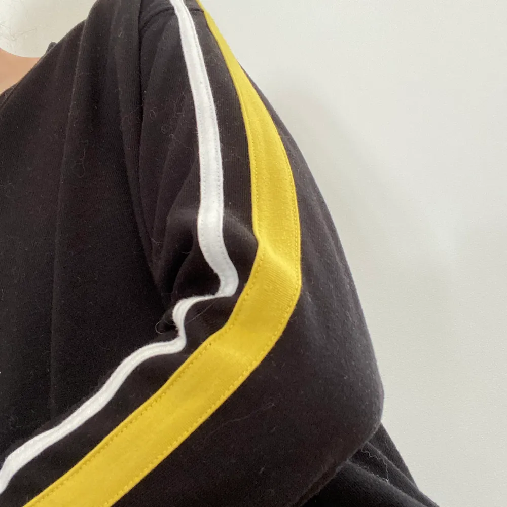 En svart sweatshirt med gula och vita revärer längst ärmarna, från H&Ms dividedavdelning. Använd ett fåtal gånger. Tveka inte att kontakta mig vid frågor!. Hoodies.