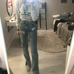 Blåa raka jeans med hål samt slits - Ljus denim raka byxor med slits nedtill, tre hål på framsidan. Supersnygga men tyvärr i fel storlek så ska beställa nya:( använda ca 2 gånger). Väldigt gult ljus på andra bilden, gå efter första för att se färg 