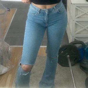 Jeans från Gina tricot storlek M - Ljusblå fina bootcut jeans i storlek M, med hål på knäna och slits längst ned på byxorna. Frakt ingår ej i priset. 