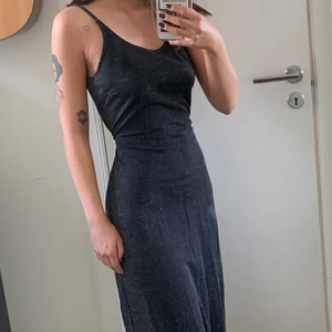 Svart glittrig långklänning - Jättefin glittrig långklänning. Man kan ha den på t.ex. bal eller nyår. Den är storlek 38/40, men jag knyter den där bak för att den ska passa mig. Sista bilden visar hur den sitter oknutet.