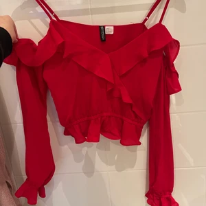 Röd blus från hm  - En röd blus från hm. Den är som ett linne och sedan är armarna off shoulder. Storlek 34. Använd Max 4 gånger. Inga hål eller fläckar. Säljer för att den inte passar längre 