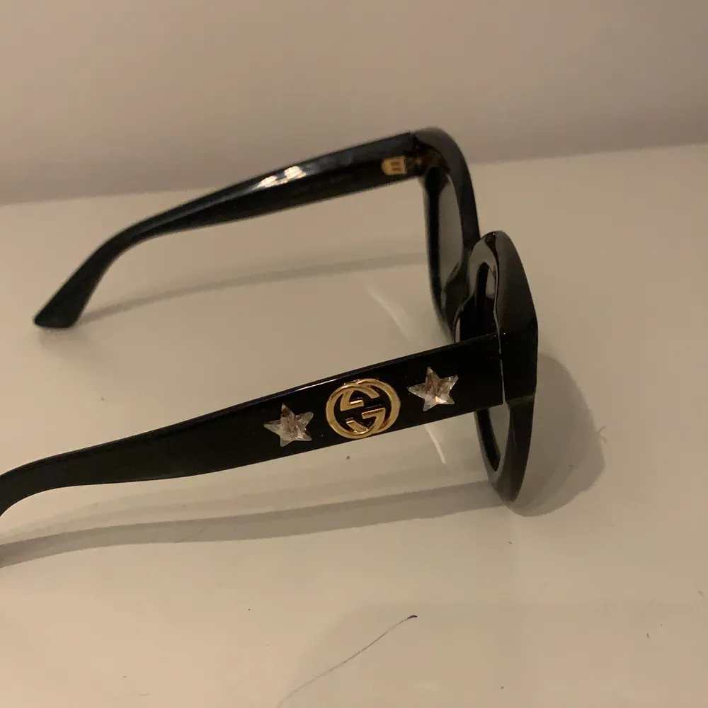 Äkta svarta Gucci solglasögon med detaljer på sidorna. Solglasögonen är i superbra skick och perfekta för den kommande sommaren! Köpt för 3500 kr. Fodral medföljer.. Övrigt.