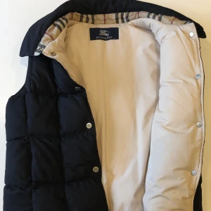 Burberry väst  - Otroligt fin väst från Burberry i storleken UK 12 (M). Perfekt skick där det inte finns några spår av användning. Väldigt liten i storleken, passar någon som vanligtvis bär storleken xs-s. Köpt från Vestiaire Collevtive april 2020 och säljer då den inte längre kommer till användning. Hör gärna av er vid frågor och funderingar🤎