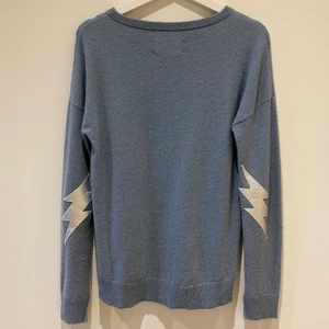 Kaschmirtröja från Zadig & Voltaire  - Blågrå Kaschmir(100%)tröja från Zadig & Voltaire med silvriga blixtar vid armbågarna. Tröjan är i fint skick. Pris: 950 kr med frakt (orginalpris: runt 3000kr)