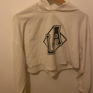 Lång armad - Det är en långärmad som är vit och svart och texten står det LA tycker det är ganska tunt det finns en luva