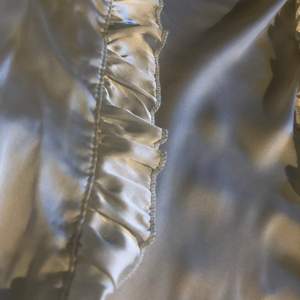 Framsida silke och baksida bomull, helvit med ett par detaljer på ärmarna. Säljer flera skjortor så skriv för ett paketpris 
